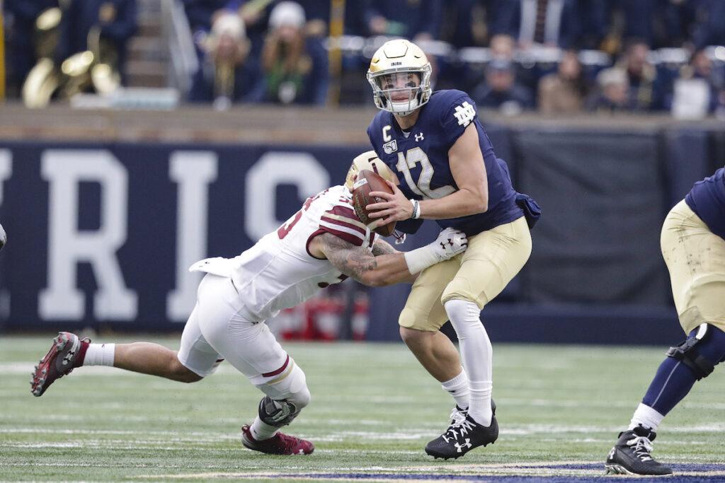 Notre Dame quarterback Ian Book (12) is hit by Boston College linebacker Isaiah McDuffie (55) as he throws during the first half of an NCAA college football game in South Bend, Ind., Saturday, Nov. 23, 2019. (AP Photo/Michael Conroy)